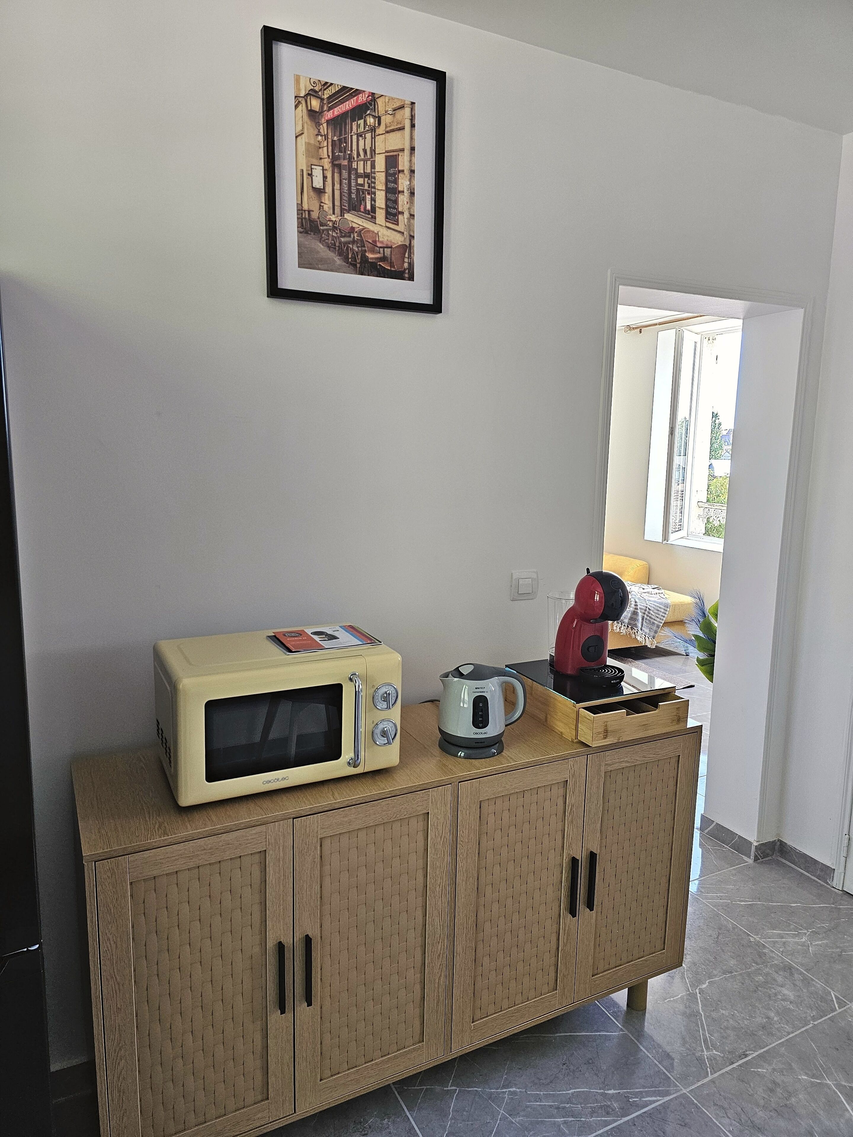 Une petite cuisine équipée d’un four à micro-ondes, d’une bouilloire et d’un grille-pain, le tout posé sur un meuble en bois.