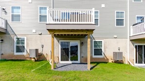 A residential building with a covered patio area, a visible air conditioning unit, and a small garden.