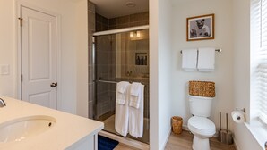 Une salle de bain avec une douche à parois de verre, des toilettes et un lavabo.