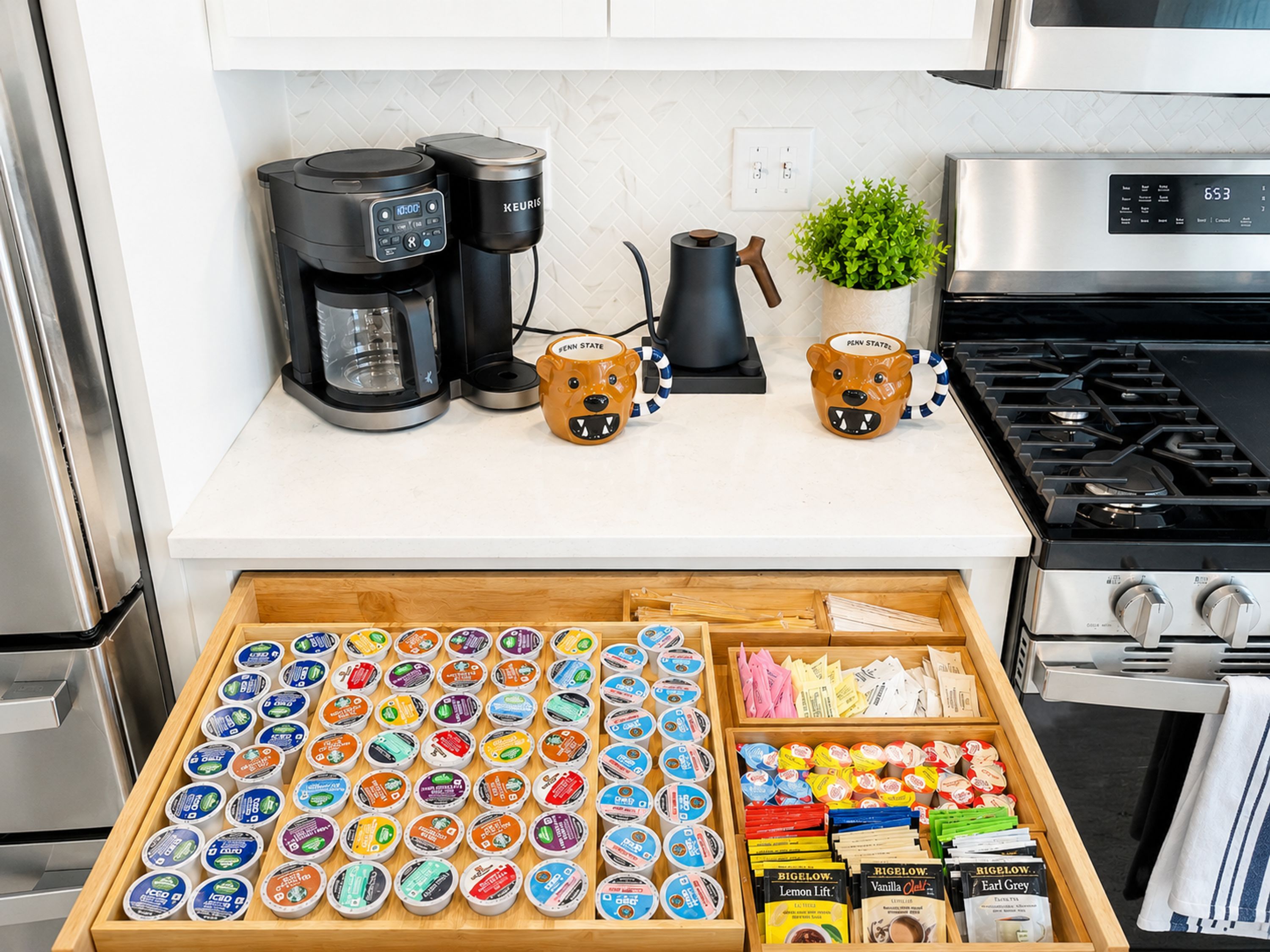 A kitchen with a coffee maker, a kettle, and a stove. Below, there is a drawer with various food items and containers.