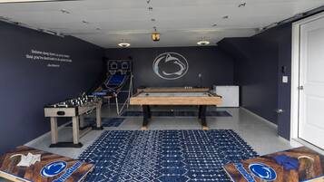 A room with a foosball table, ping pong table, and a pool table.