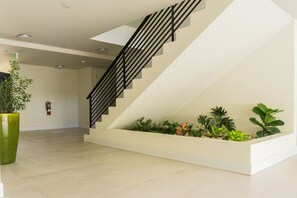 Eine moderne Treppe mit schwarzer Geländer, einer weißen Wand und einem bepflanzten Blumentopf am Fuß.