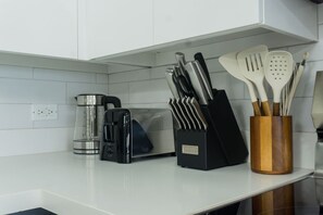 Eine Küchenarbeitsplatte mit Kaffeemaschine, Toaster und einem Besteckhalter.