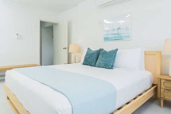 Ein Hotelzimmer mit einem Einzelbett, einem Nachttisch, einer Lampe und einem an der Wand hängenden Bild.