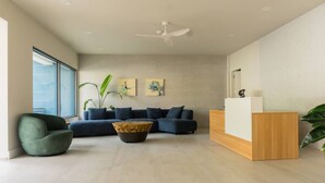 Una sala de estar moderna con un conjunto de sofás, una mesa de centro, un sillón verde, una recepción y un ventanal grande.