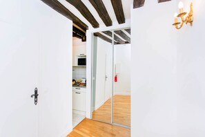 A hallway with a wooden floor, white walls, and a sliding glass door leading to a kitchen area. - Lovely 1BR Flat by The Louvre - Rivoli (Paris)