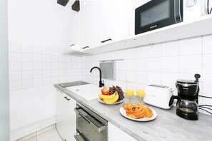 A modern kitchen with white cabinets, a stainless steel sink, a toaster, a coffee maker, and a fruit plate. - Lovely 1BR Flat by The Louvre - Rivoli (Paris)