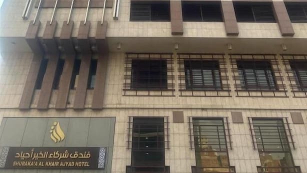 Um edifício alto de hotel com design moderno, apresentando um logotipo e sinalização destacados para o Shuraka' Al Khair Ajwad Hotel.