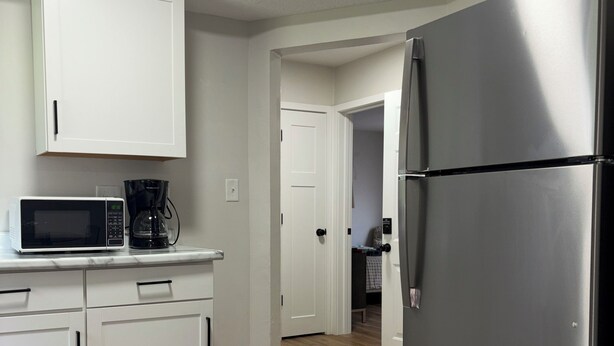 A kitchen with white cabinets, a stainless steel refrigerator, and a microwave. - Cozy, contemporary apartment outside of the Fort Wayne city center (Fort Wayne)