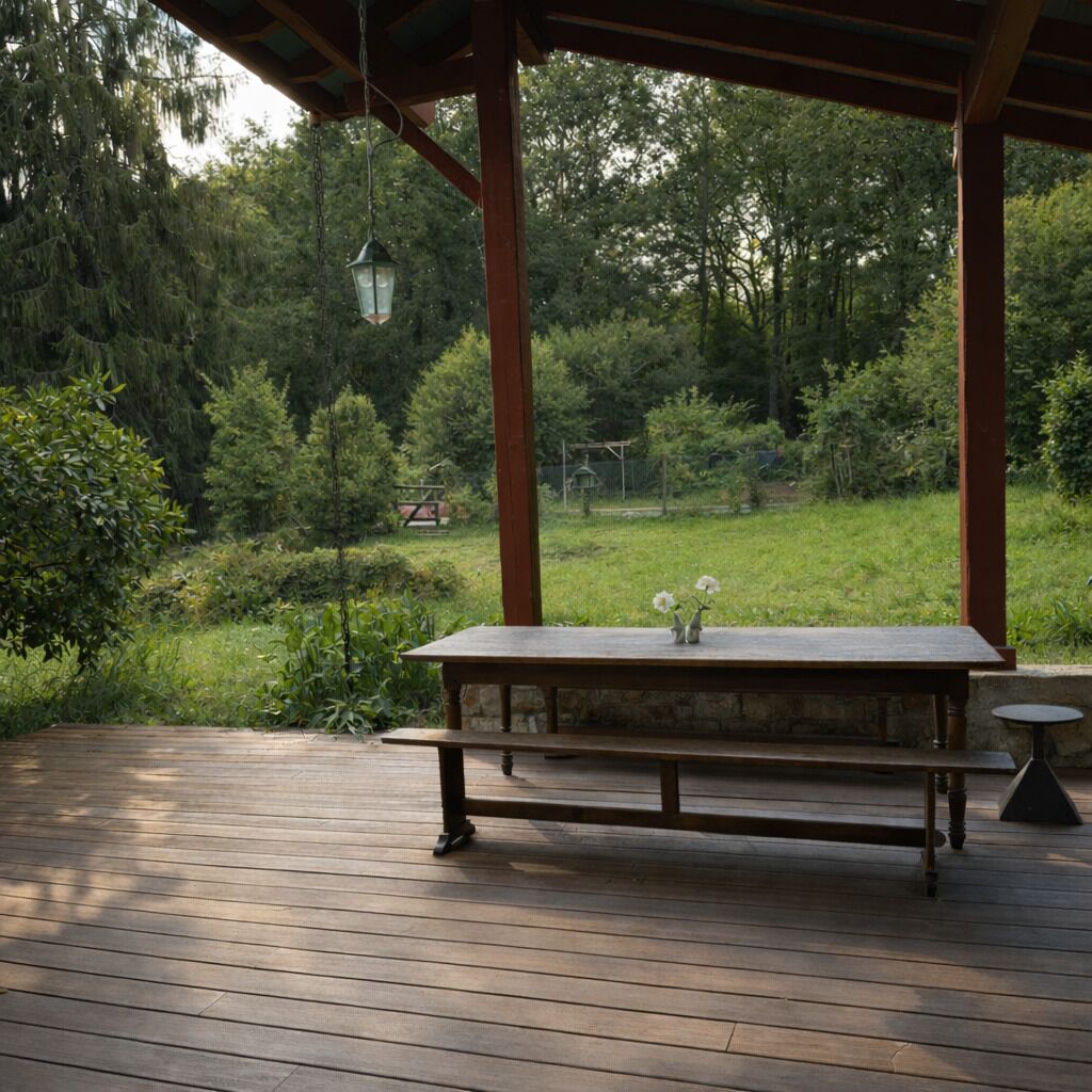 Een houten terras met een tafel en stoelen, omgeven door weelderig groen en bomen.