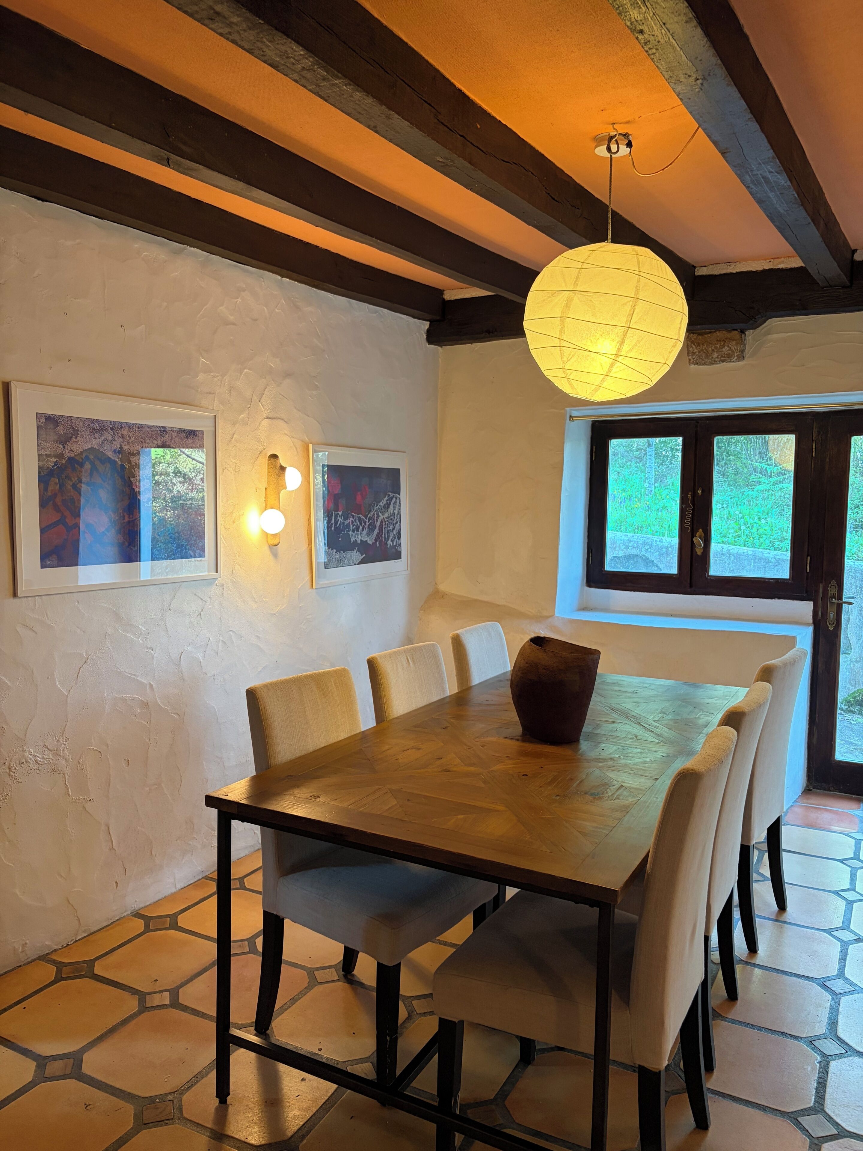 Een eethoek met een houten tafel en stoelen, kunst aan de muur en een hanglamp.