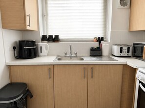 A kitchen with a sink, coffee maker, toaster, and cabinets. - Near Wembley Stadium- 1 Bedroom Flat (Wembley)