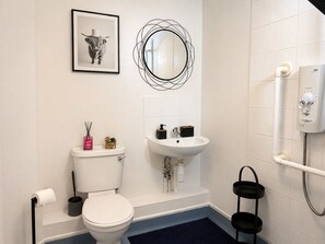 A bathroom with a toilet, sink, and shower. There is a framed picture on the wall and a mirror with a unique design. - Near Wembley Stadium- 1 Bedroom Flat (Wembley)