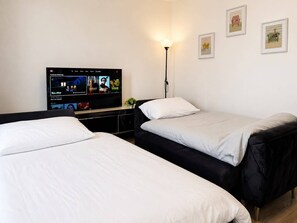 Een hotelkamer met twee bedden, een televisie en een lamp.