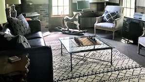Un salon avec une cheminée, un cheval à bascule, un jeu d’échecs et un tapis à motifs.