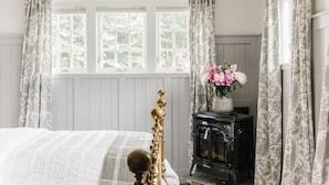 Une chambre à coucher avec un lit, une commode, un radiateur et une fenêtre avec des rideaux.