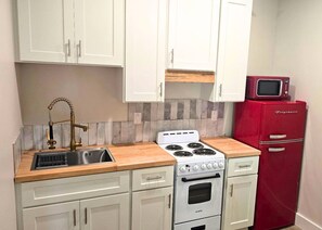 A compact kitchen with a white stove, a red refrigerator, and a stainless steel sink with a brass faucet. - New Hotel Suite Near Downtown Ocean Springs with Pool Access (Ocean Springs)
