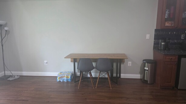 A room with a wooden table, two chairs, a trash bin, and a cabinet. - Comfortable private retreat in the Ashburn, VA (Ashburn)