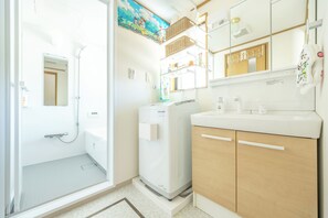 A bathroom with a shower, a toilet, and a sink with a mirror above it. - Vrbo Property (江戸川区)