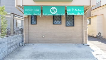 A building entrance with a green awning displaying 'OMITAMA HOME' and 'KOBE HOME'.