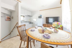 A dining area with a round table, chairs, and a vase with flowers. - Vrbo Property (江戸川区)