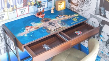 A desk with a One Piece-themed tabletop, drawers, and a chair.