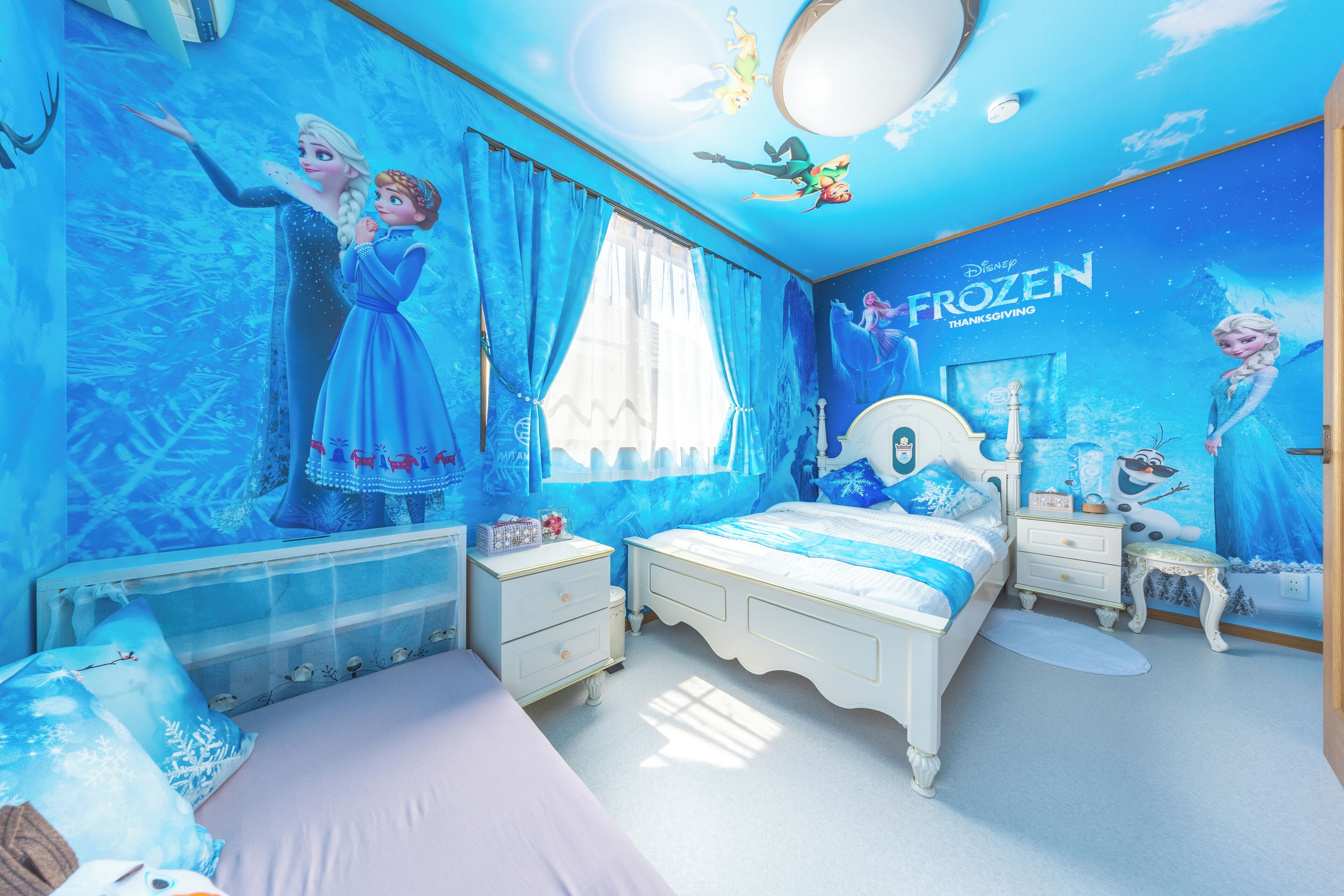 A bedroom with a bed, nightstands, a dresser, and a wall mural of Frozen characters.