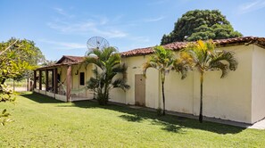 A building with a tiled roof, a covered porch, and a small garden area with palm trees.