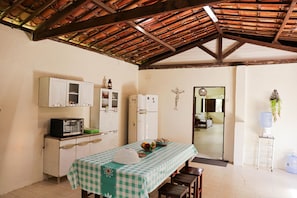 A kitchen with a table set for dining, a refrigerator, and a wall-mounted cross.