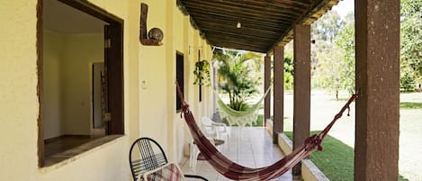 A covered outdoor area with a hammock, a chair, and a small table.