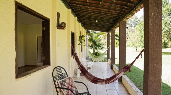 A covered outdoor area with a hammock, a chair, and a small table.