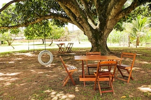 A wooden table and chairs set under a large tree in a park.