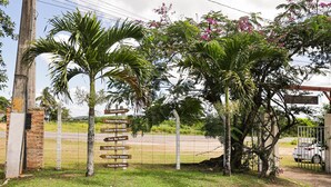 A signpost with multiple directional arrows, a brick wall, and a grassy area with scattered stones.