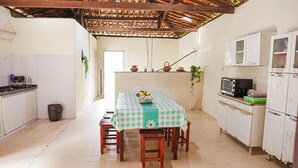 A kitchen with a table set for four, a microwave, and cabinets. - Rancho Alegre c/ Wi-fi, Ar Condicionado e Natureza (Itabaiana)