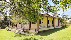 A single-story building with a porch, steps leading to the entrance, and a small garden area.
