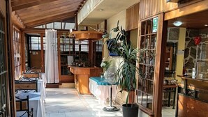 Un hall d’hôtel avec un sol carrelé, des meubles en bois et un comptoir d’accueil.