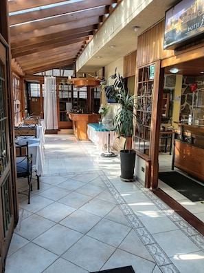 A hotel lobby with a tiled floor, wooden furniture, and a reception desk. - HOTEL 3 PONIENTE (Viña del Mar)