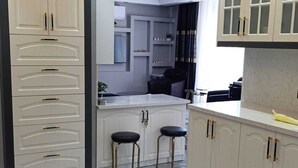Una cocina moderna con armarios blancos, encimera de mármol y alfombra negra y gris.
