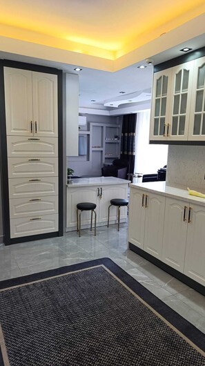 A modern kitchen with white cabinetry, a marble countertop, and a black and gray rug. - Stunning 2-Bedroom Villa with Heated Pool & Jacuzzi in Antalya, Kemer (Antalya)