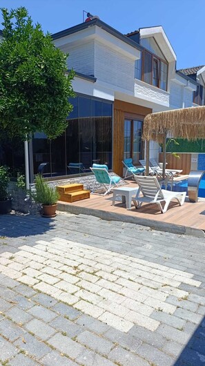 Un bâtiment moderne doté d’un espace piscine, comprenant des chaises longues et une terrasse en bois.