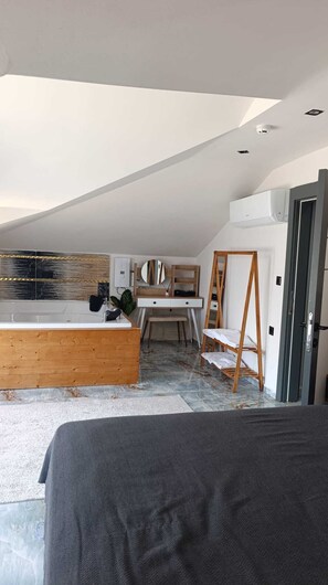 Une chambre de style loft moderne, avec un plafond en pente, un bureau en bois, un grand miroir et une vue sur la ville.
