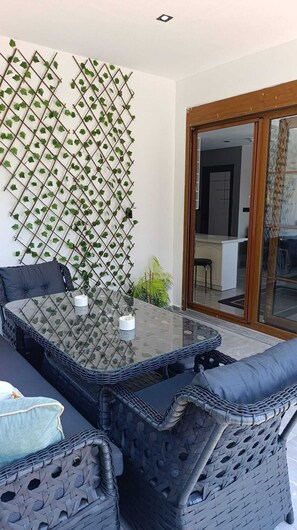 A glass-top table with a woven chair, a wall-mounted plant, and a sliding glass door leading to a room. - Stunning 2-Bedroom Villa with Heated Pool & Jacuzzi in Antalya, Kemer (Antalya)