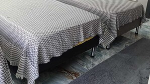 Un dormitorio moderno con dos camas, una pared oscura y una alfombra gris.