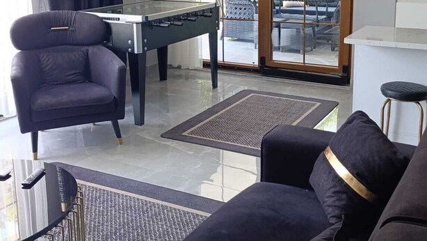 Una sala de estar moderna con mesa de billar, un sofá y una mesa de centro de vidrio.