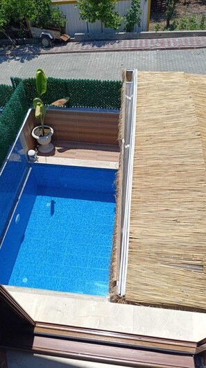 A rooftop pool with a clear blue water surface, surrounded by a wooden deck and a small potted plant. - Stunning 2-Bedroom Villa with Heated Pool & Jacuzzi in Antalya, Kemer (Antalya)