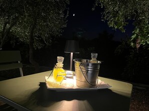 Ein Tisch mit einer Flasche, einer Lampe und einem Eimer, draußen bei Nacht.