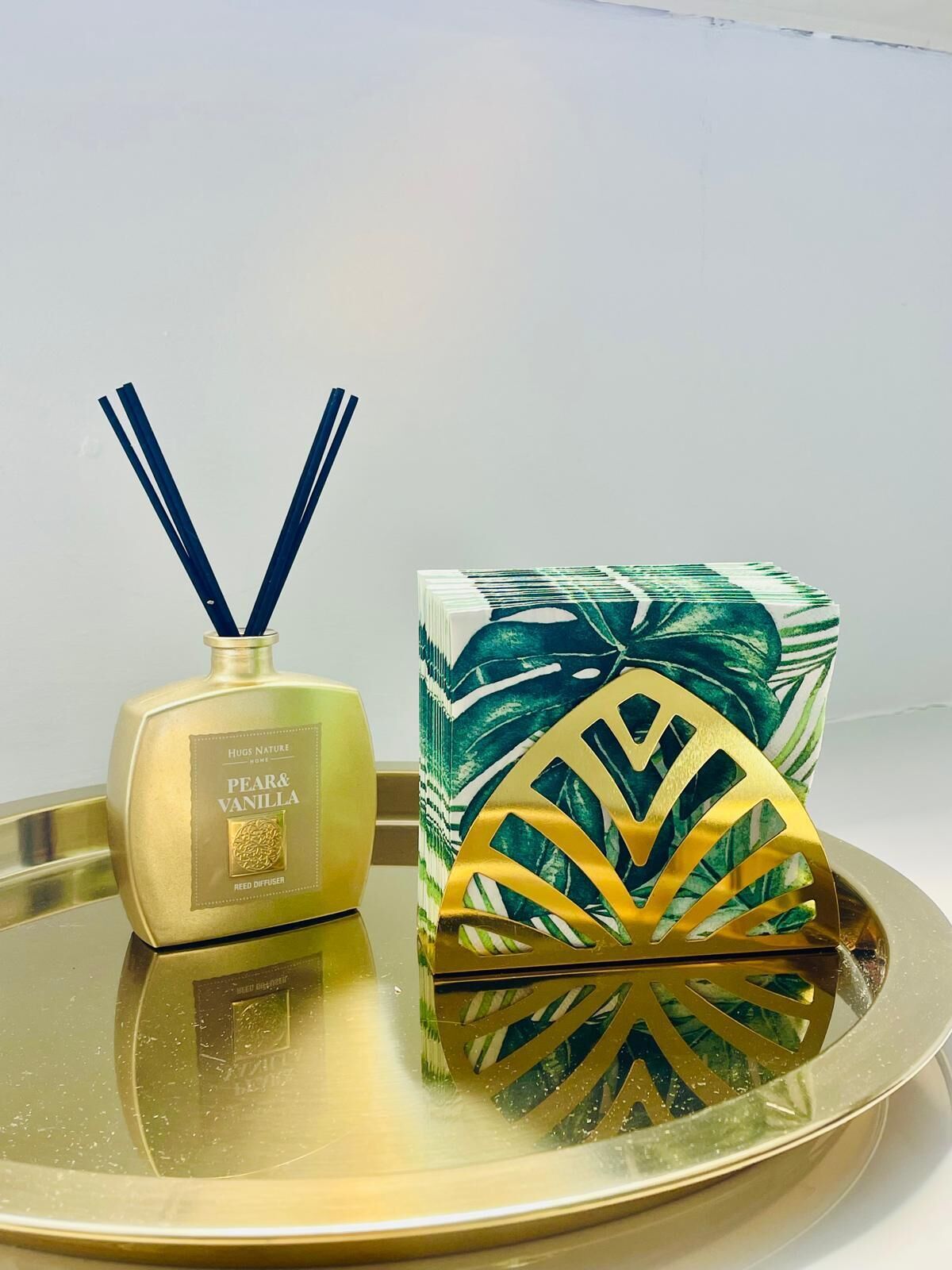 A gold diffuser and a decorative box with a geometric pattern on a reflective tray.