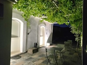 An outdoor patio area with a table and chairs, a small trash bin, and a door leading to the interior.