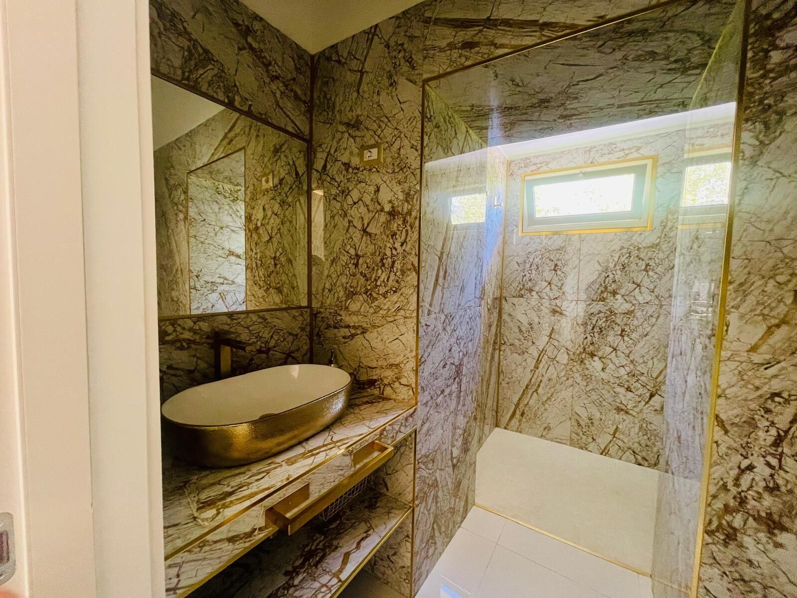 Une salle de bain avec un mur en marbre, un lavabo et une douche.