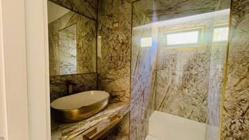 Une salle de bain avec un mur en marbre, un lavabo et une douche.